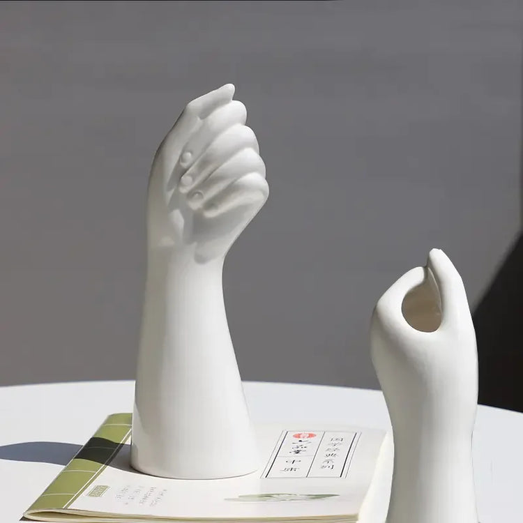Modern ceramic hand sculptures on a table with a book, minimalist home decor