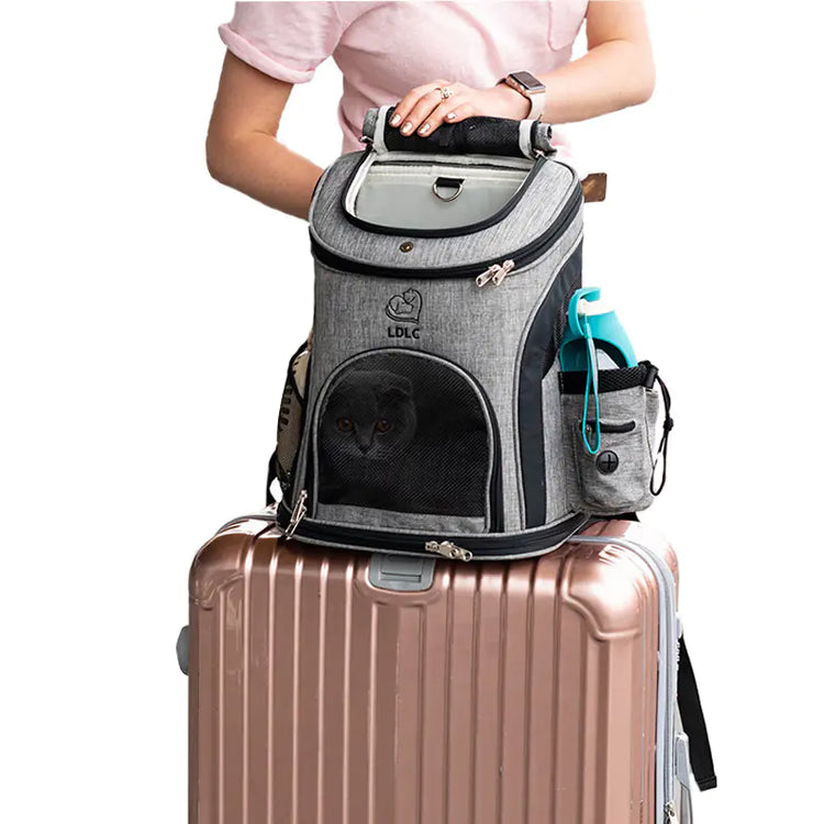 Traveler with cat carrier backpack on suitcase, grey pet travel backpack and water bottle