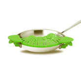 Green silicone clip-on strainer attached to a stainless steel frying pan