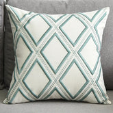 Decorative throw pillow with blue geometric diamond pattern on a grey sofa