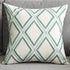 Decorative throw pillow with blue geometric diamond pattern on a grey sofa