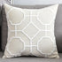 Beige decorative throw pillow with geometric white embroidery on grey sofa