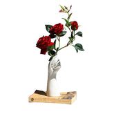 Ceramic hand vase with red roses on a book, displayed on a white round table
