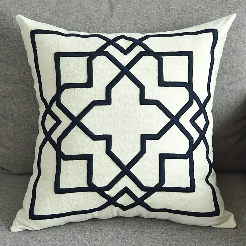 Modern decorative throw pillow with black geometric pattern on a light fabric on gray sofa