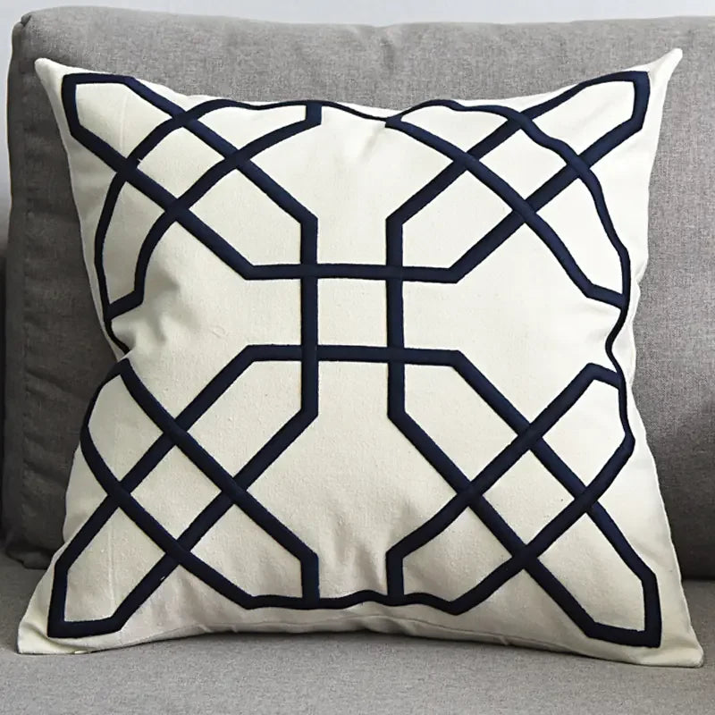 Modern decorative throw pillow with geometric black pattern on white fabric on grey sofa