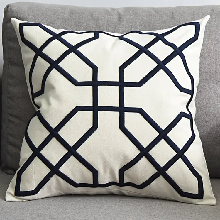 Modern decorative throw pillow with geometric black pattern on white fabric on grey sofa
