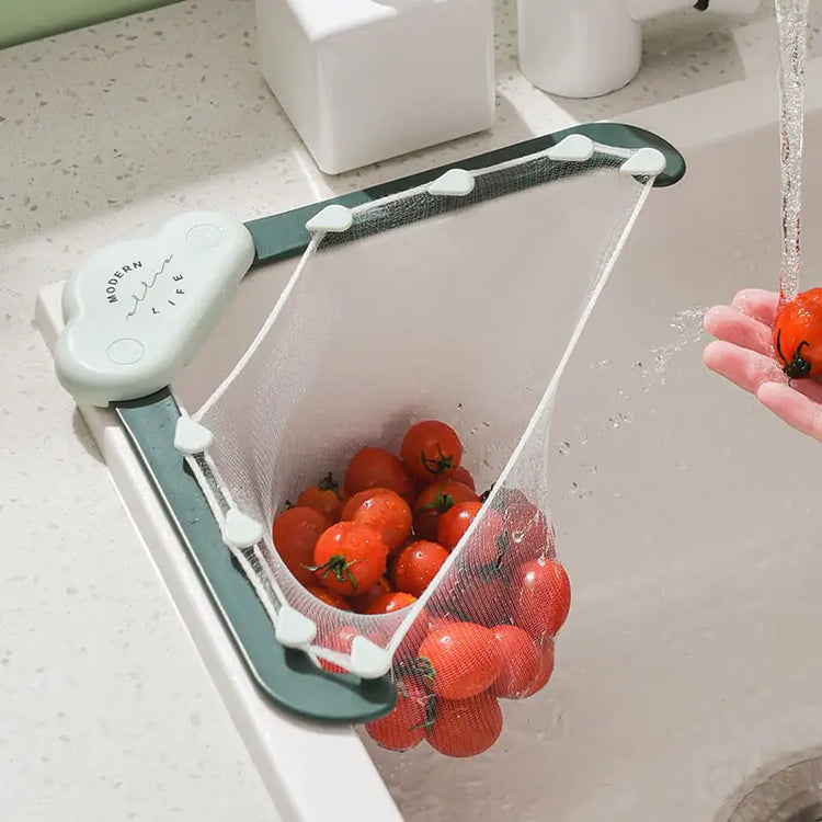 Mesh sink strainer holding cherry tomatoes under running water in a modern kitchen