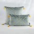 Velvet throw pillows with gold geometric lines and yellow tassels on a plain backdrop