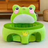 Plush green frog baby seat with pink cheeks and a crown design on the front, indoor setting