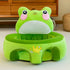 Plush green frog baby seat with pink cheeks and a crown design on the front, indoor setting