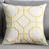 Yellow geometric embroidered throw pillow on a gray sofa