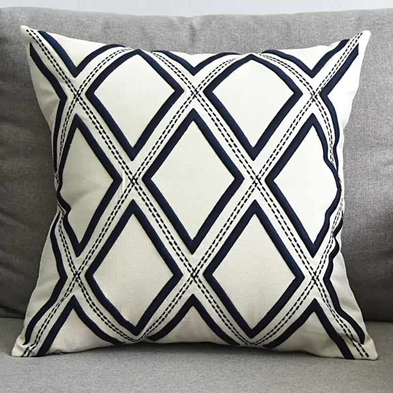 White throw pillow with black diamond geometric pattern on a grey sofa