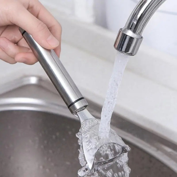 Stainless steel vegetable peeler rinsed under kitchen faucet in modern sink