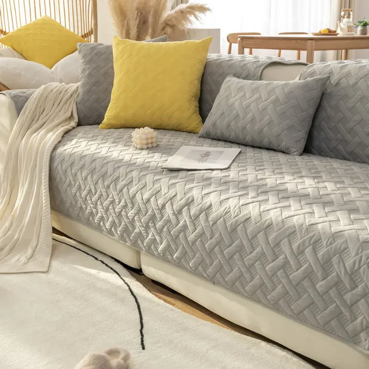 Modern living room with a grey quilted sofa cover, yellow and grey pillows, and cozy decor