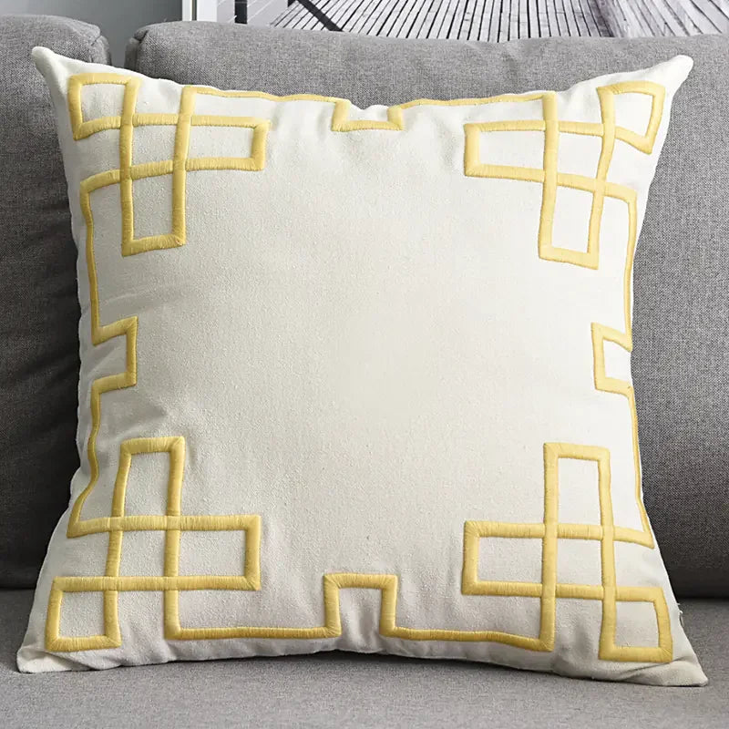 Cream throw pillow with yellow geometric pattern on a gray sofa