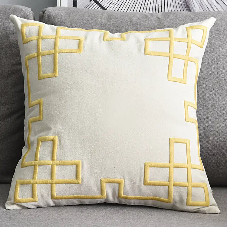 Cream throw pillow with yellow geometric pattern on a gray sofa
