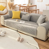 Modern living room with a gray quilted sofa cover, yellow cushion, and soft white rug