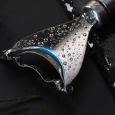 Stainless steel kitchen scraper with water droplets on black surface