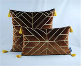 Brown velvet throw pillows with gold geometric lines and yellow corner tassels