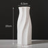 White ceramic vase with twisted design, 20cm tall, 6.3cm top, 8.6cm base, on grey surface