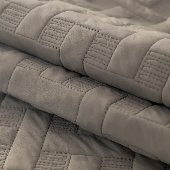 Folded grey quilted blanket with soft textured stitching detail