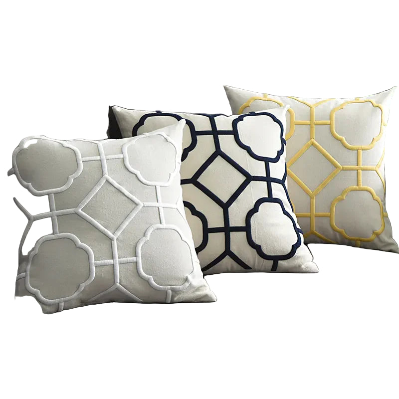 Modern sofa with three geometric decorative throw pillows, plant and wall art decor