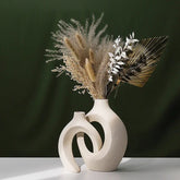 Modern abstract beige ceramic vase with dried pampas grass, palm leaf, and white foliage