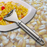 Stainless steel corn peeler on plate of mixed corn and vegetables, corn background