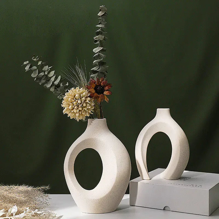 Modern ceramic open vases with dried flowers on white table, green background, minimalist decor