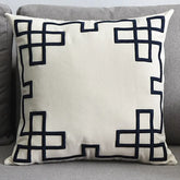 Modern beige throw pillow with black geometric border on a grey sofa