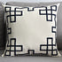 Modern beige throw pillow with black geometric border on a grey sofa