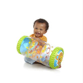 Smiling baby playing with inflatable colorful baby activity rolling toy on white background